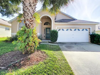 a house with a palm tree in front of a driveway at Cinderellas Castle in Kissimmee