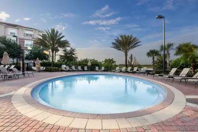 a large swimming pool with chairs and palm trees at Chantilly Condo - closer to Disney and Universal in Orlando