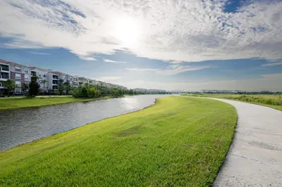 a river with green grass and buildings in the background at Chantilly Condo - closer to Disney and Universal in Orlando