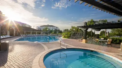a pool at a resort with a table and chairs at Merlyns Magic Condo - closer to Disney in Orlando