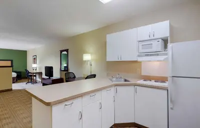 a kitchen with white cabinets and a living room at Extended Stay America Suites - Orlando - Orlando Theme Parks - Major Blvd in Orlando