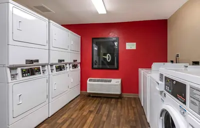 a laundry room with white washers and a red wall at Extended Stay America Suites - Orlando - Orlando Theme Parks - Major Blvd in Orlando