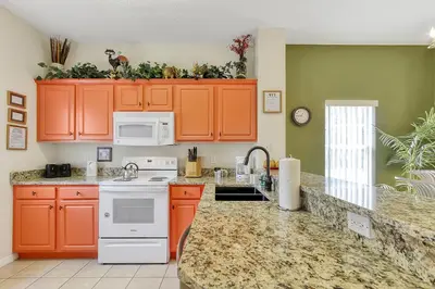 a kitchen with orange cabinets and white appliances at Emerald Delight 3 bed townhome near Disney in Kissimmee