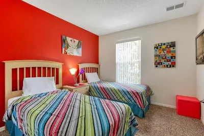 two beds in a room with red walls at Emerald Delight 3 bed townhome near Disney in Kissimmee