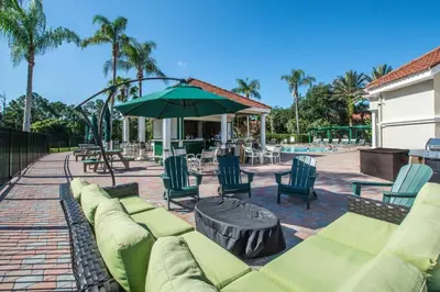 a patio with a couch and chairs and an umbrella at Emerald Delight 3 bed townhome near Disney in Kissimmee
