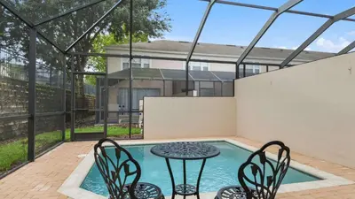 a patio with a table and chairs next to a pool at Minnies Townhouse in Windsor Palms Resort in Kissimmee