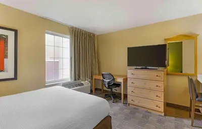a hotel room with a bed and a desk with a television at Extended Stay America Select Suites - Orlando - Southpark - Equity Row in Orlando
