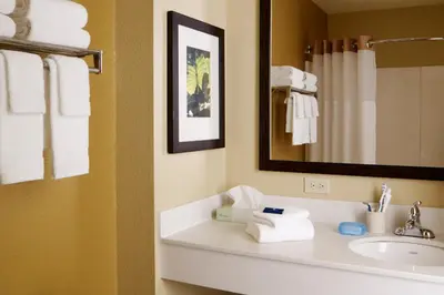 a bathroom with a sink and a mirror and towels at Extended Stay America Select Suites - Orlando - Maitland - Summit Tower Blvd in Orlando
