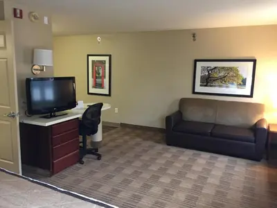 a room with a couch and a desk with a television at Extended Stay America Select Suites - Orlando - Maitland - Summit Tower Blvd in Orlando