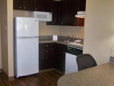 a kitchen with a white refrigerator and black cabinets at Extended Stay America Select Suites - Orlando - Maitland - Summit Tower Blvd in Orlando