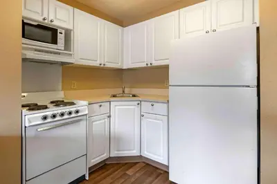 a kitchen with white cabinets and a white refrigerator at Extended Stay America Suites - Orlando - Convention Center - 6443 Westwood in Orlando