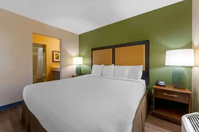 a bedroom with a large bed with white sheets and green walls at Extended Stay America Suites - Orlando - Convention Center - 6443 Westwood in Orlando