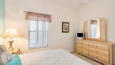 a bedroom with a bed and a dresser and a mirror at Bikini on the Beach at Terra Verde Resort in Kissimmee