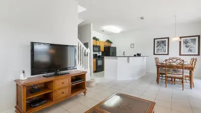 a living room with a flat screen tv on a wooden entertainment center at Encantada Rose - a 4 bed townhouse near Disney in Kissimmee