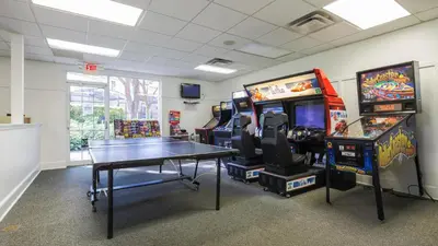 a gaming room with two arcade games and a table at Encantada Rose - a 4 bed townhouse near Disney in Kissimmee