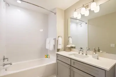 a white bathroom with a tub and a sink and a tub and a mirror at Siena at Bella Collina in Montverde