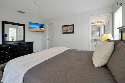 a bedroom with a bed and a dresser and a television at Bikini Bottom - 4 bed Disney pool home in Kissimmee