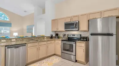 a kitchen with wooden cabinets and stainless steel appliances at Disney Backstage Villa - Stay in this popular 4 bed pool home that's very close to Disney in Orlando