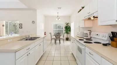 a kitchen with white cabinets and a table in it at Lucky Charm - Budget-friendly 5 bed vacation home, close to Disney World in Kissimmee