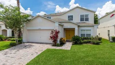 a large white house with a garage at Lucky Charm - Budget-friendly 5 bed vacation home, close to Disney World in Kissimmee
