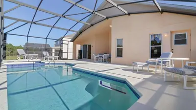 a swimming pool with chairs and tables and a building at Waterside Villa - Family 4 bed Emerald Island Resort pool home that's close to Disney World in Kissimmee