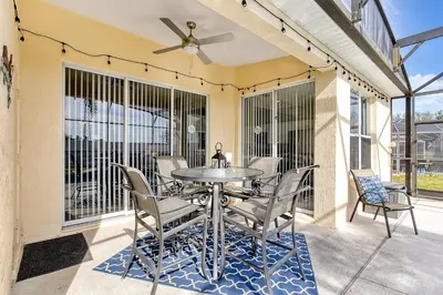 a patio with a table and chairs and a ceiling fan at Sunshine Station - Spacious 4 bed Windsor Palms resort home that's close to Disney in Kissimmee