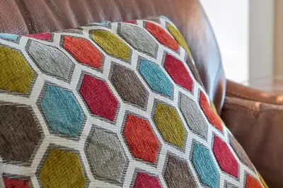 a colorful pillow on a leather couch at Disney Magic Vacation - A fabulous 4 bed family pool home on Windsor Palms Resort - close to Disney World in Kissimmee