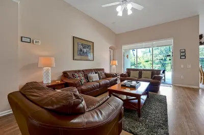 a living room with a leather couch and a table at Disney Magic Vacation - A fabulous 4 bed family pool home on Windsor Palms Resort - close to Disney World in Kissimmee