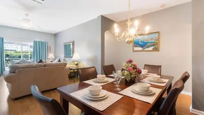 a dining room and living room with a table and chairs at Rhapsody Palms - Family 4-bed pool home that's close to Disney in Kissimmee
