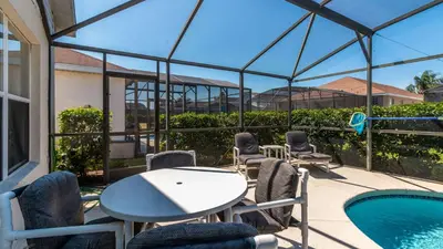 a patio with a table and chairs and a pool at Rhapsody Palms - Family 4-bed pool home that's close to Disney in Kissimmee