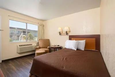a hotel room with a bed and a chair and a window at Rodeway Inn Kissimmee - Orlando Maingate West - Free Theme Park Shuttle in Orlando