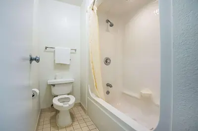a white bathroom with a toilet and a shower at Rodeway Inn Kissimmee - Orlando Maingate West - Free Theme Park Shuttle in Orlando