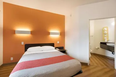 a bedroom with a bed with an orange wall at Motel 6-Orlando, FL - International Dr in Orlando