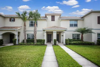 a large white house with palm trees in the yard at F - New 4 Bedroom Home - 5 Miles to Disney - Free Water Park - Private Pool in Kissimmee
