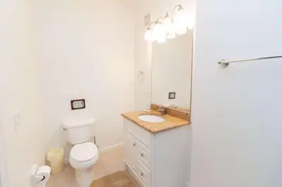 a white bathroom with a toilet and a sink at 5min Universal Spacious Condo VC101 in Orlando