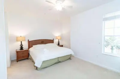a white bedroom with a bed and a window at 5min Universal Spacious Condo VC101 in Orlando