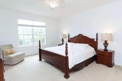 a bedroom with a bed and a chair and a window at 5min Universal Spacious Condo VC101 in Orlando