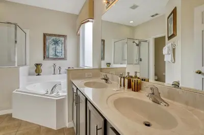 a bathroom with two sinks and a large mirror at Mickeys Sunspot - 6 bed Emerald Island Resort pool home in Kissimmee