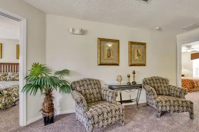 a room with two chairs and a table and a bed at Mickeys Sunspot - 6 bed Emerald Island Resort pool home in Kissimmee