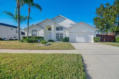 a white house with palm trees and a sidewalk at Quiet Home With Private Pool- Near Disney in Kissimmee