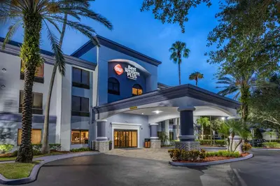 a hotel with palm trees in front of a building at Best Western Plus Orlando East - UCF Area in Orlando
