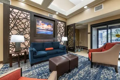 a living room with a blue couch and chairs at Best Western Plus Orlando East - UCF Area in Orlando