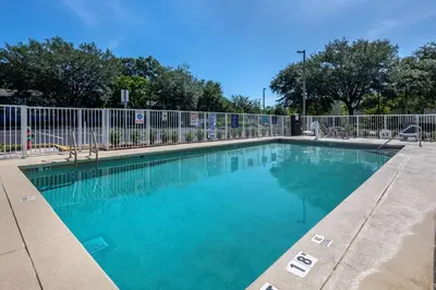 a swimming pool with a fence and blue water at Best Western Plus Orlando East - UCF Area in Orlando