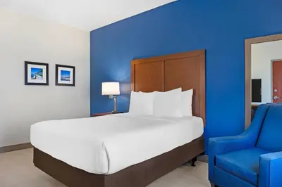 a bedroom with a large bed and a blue wall at Comfort Inn & Suites Orlando North in Sanford