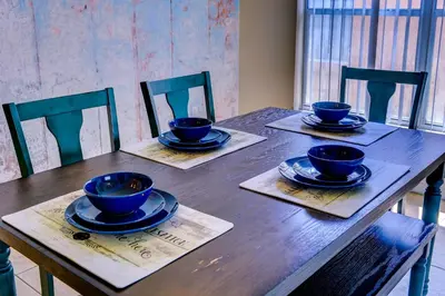 a wooden table with four blue bowls and plates on it at Fascinating Lake View With Private Pool And Game-Room, Near Disney!! in Kissimmee