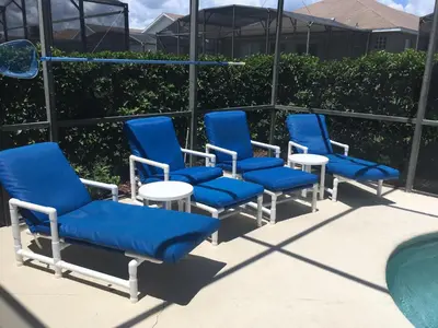 a group of blue chairs and tables next to a pool at Mickey Holiday Home a Windsor Palms Villa in Kissimmee