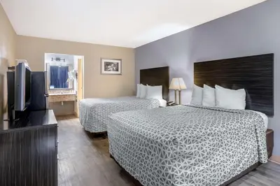 a hotel room with two beds and a flat screen tv at Suburban Studios International Drive in Orlando