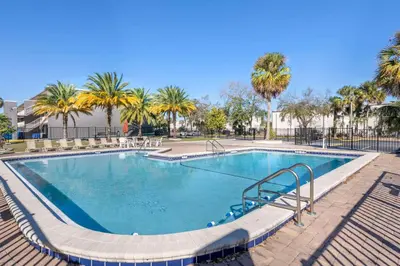 a large swimming pool with trees and palm trees at Suburban Studios International Drive in Orlando