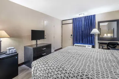 a hotel room with a bed and a flat screen tv at Suburban Studios International Drive in Orlando