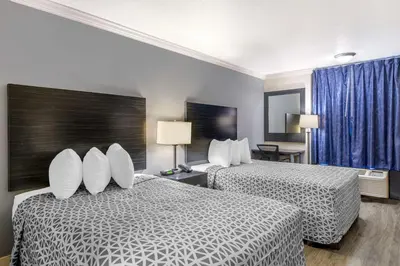 a hotel room with two beds with white pillows at Suburban Studios International Drive in Orlando